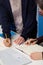 Vertical shot of two office workers signing a document