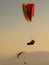 Vertical shot of two people paragliding above the mountains during the sunset in the evening