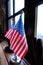 Vertical shot of the U.S. flags placed on a table beside a window