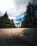 Vertical shot of an unpaved path through a park leading to a beautiful white castle