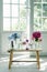 Vertical shot of the vases of beautiful flowers on a wooden chair