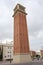 Vertical shot of the Venetian tower made of artificial stone an red brick with its pyramidal copper roof. Avinguda de la Reina