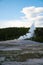 Vertical shot of a volcanic steam coming out of geyser hole in ground.
