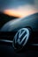 Vertical shot of the Volkswagen Logo on Black Car with a sunset view in the background