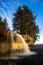 Vertical shot of a waterfall under a cloudy blue sky in Sandcut Regional Park in Canada