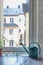 Vertical shot of a watering can near the window with buildings outside