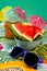 Vertical shot of watermelon wedges,carrot juice,tiny umbrellas and  sunglass on colorful tablecloth