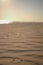 Vertical shot of wet sand with wavy pattern on beach with blurry ocean background