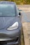 Vertical shot of a wet Tesla electric car charging at the charge station.