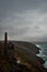 Vertical shot of Wheal Coats in Cornwall, UK with gray clouds and sea crashing the cliffs