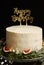 Vertical shot of a white happy birthday dream cake with green leaves at the bottom