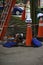 Vertical shot of a white hard hat on top of a safety cone with an extension ladder on a sidewalk