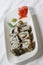 Vertical shot of a white plate of tasty sushi rolls with black and white sesame seeds