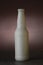 Vertical shot of a white soda/beer bottle with water drops and a black backdrop