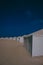 Vertical shot of white tents on the sandy beach underneath a beautiful blue sky