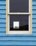 Vertical shot of a window on a wooden blue wall of a cottage