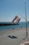 Vertical shot of windsocks hanging from a pole with people standing near the sea in background