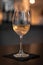 Vertical shot of a wine glass semi-full of white wine on the table, a black napkin under it