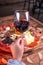 Vertical shot of a woman holding a glass of wine behind a variety of meat assortment