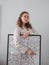 Vertical shot of a woman posing with a framed artwork on the background of a white wall