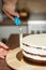 Vertical shot of a woman smoothing edges of a chocolate cake with a spatula, in the kitchen