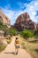 Vertical shot of a woman walking on a pathway with a beautiful Angels Landing rock formation