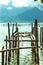 Vertical shot of wood pilings on the water surface against green mountains on the shore. Vietnam.