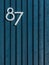 Vertical shot of a wooden blue wall with vertically arranged sticks and white number eighty-seven
