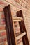 Vertical shot of a wooden foldable ladder leaned against a brick wall