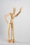 Vertical shot of a wooden pose doll with one hand in the air on a white background