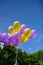 Vertical shot of yellow and purple helium balloons in the sky