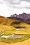 Vertical shot of a yellow valley in front of the dark rocks and the cloudy sky in the background