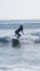 Vertical shot of a young attractive female in a wetsuit surfing at the beach