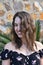 Vertical shot of a young caucasian female elegantly smiling in front of the wall