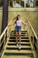 Vertical shot of a young caucasian female posing while standing on the yellow stairs of a building