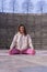 Vertical shot of a young caucasian woman is stretching her body in a yoga pose on a pink mat