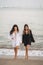 Vertical shot of young Europeans female wearing black and white dress standing on the seashore