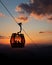Vertical silhouette shot of people inside a ropeway wagon during sunset