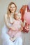 Vertical smiling, cheerful blonde woman, mother carrying baby in pink dress and flower on head, one year celebrating