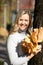 Vertical smiling woman, picking up, holding bunch golden foliage yellow leaves maples, touch hair, ivy decor blur. Close