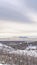 Vertical Snow covered mountain with road overlooking a valley under cloudy sky in winter