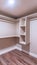 Vertical Spacious walk in closet of new home with metal rods shelves and wooden floor