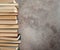 A vertical stack of books in close-up against a gray concrete wall.