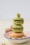 A vertical stack of colorful macaroons in a dish with nuts