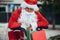 Vertical stock photo of santa claus supported in a bicycle full of gifts with exhausted expression. Christmas time