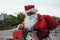 Vertical stock photo of santa claus supported in a bicycle full of gifts with exhausted expression. Christmas time