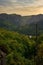 Vertical of a streetlamp against a mountain range covered with a green forest at sunset