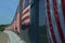 Vertical stripes of American flags on sunny side of highway overpass fence