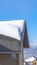 Vertical Sunlit gray pitched roof of a home with mound of fresh snow at winter season