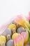 Vertical tender spring Easter composition of paschal eggs pink tulips on white background